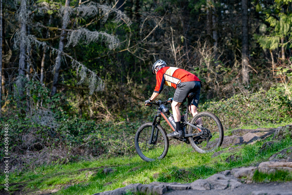 Elderly man riding a mountain bike along a rocky forest path Elderly man riding a mountain bike along a rocky forest path