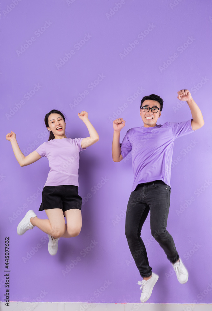 Young Asian couple jumping on purple background Young Asian couple jumping on purple background
