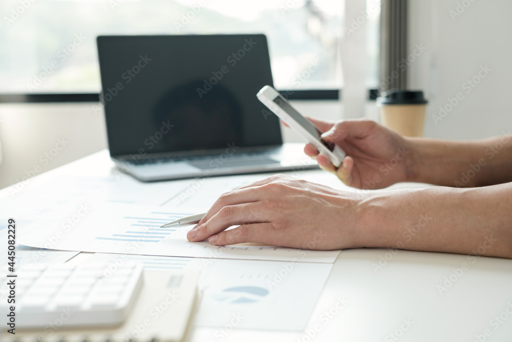 Fototapeta premium work from home, The hand of a man who works in finance sits at his desk at home and calculates financial graphs showing the results of his investments, planning the steps of his business growth