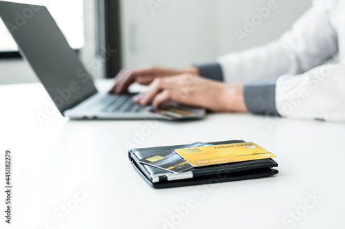 The businessman's hand is holding a credit card and using a laptop for online shopping and internet payment