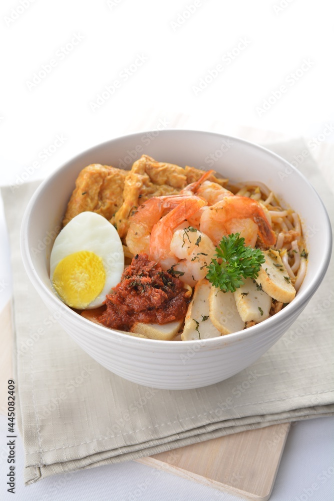spicy nyonya noodle laksa soup with seafood prawn, fish cake, egg, bean curd and chilli sambal sauce in white background asian halal menu