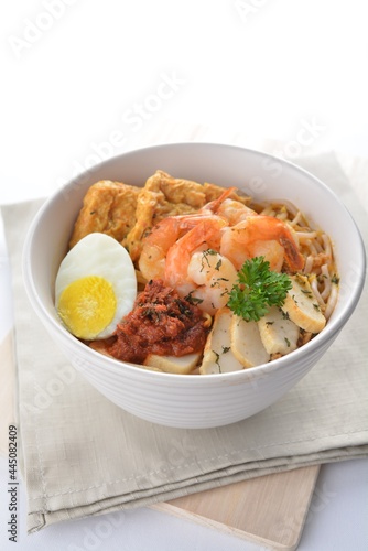 spicy nyonya noodle laksa soup with seafood prawn, fish cake, egg, bean curd and chilli sambal sauce in white background asian halal menu
