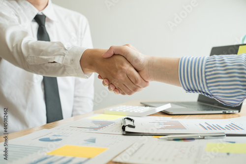 Two business leaders talk about charts, financial graphs showing results are analyzing and calculating planning strategies, business success building processes, and shake hands