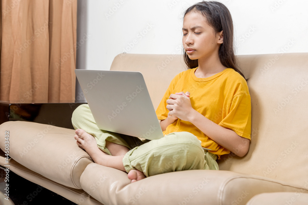 Asian little girl with a laptop feels tired on online school class at home Asian little girl with a laptop feels tired on online school class at home