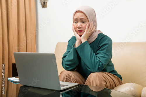 Asian Muslim businesswoman using a laptop working from home