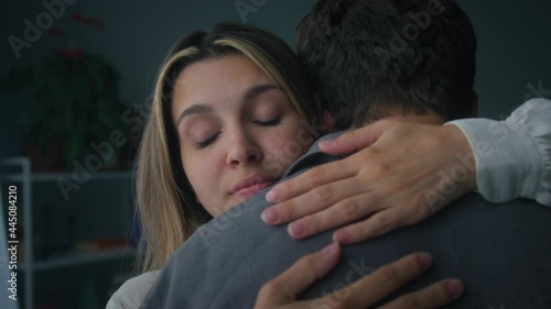 Lovely woman hugging man, wife and husband reconciling after conflict, standing in living room. Young married couple supporting each other, forgiving and cuddling. 