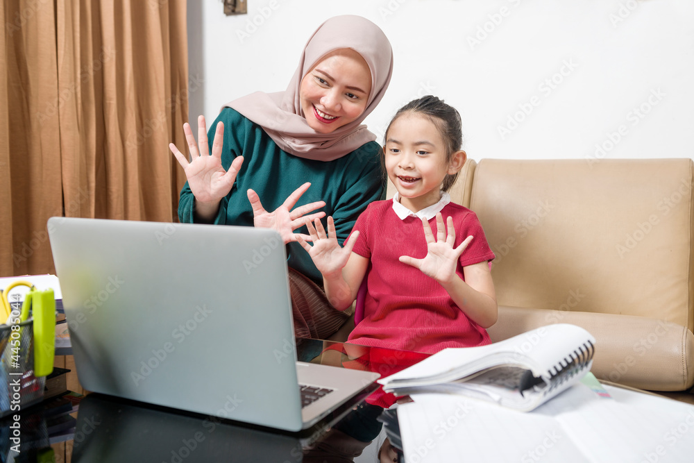 Asian mother helping little girl doing her homework with laptop at home Asian mother helping little girl doing her homework with laptop at home