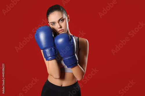 Sporty female coach in boxing gloves on color background © Pixel-Shot