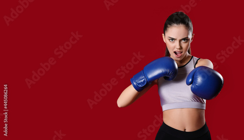 Sporty female coach in boxing gloves on color background © Pixel-Shot