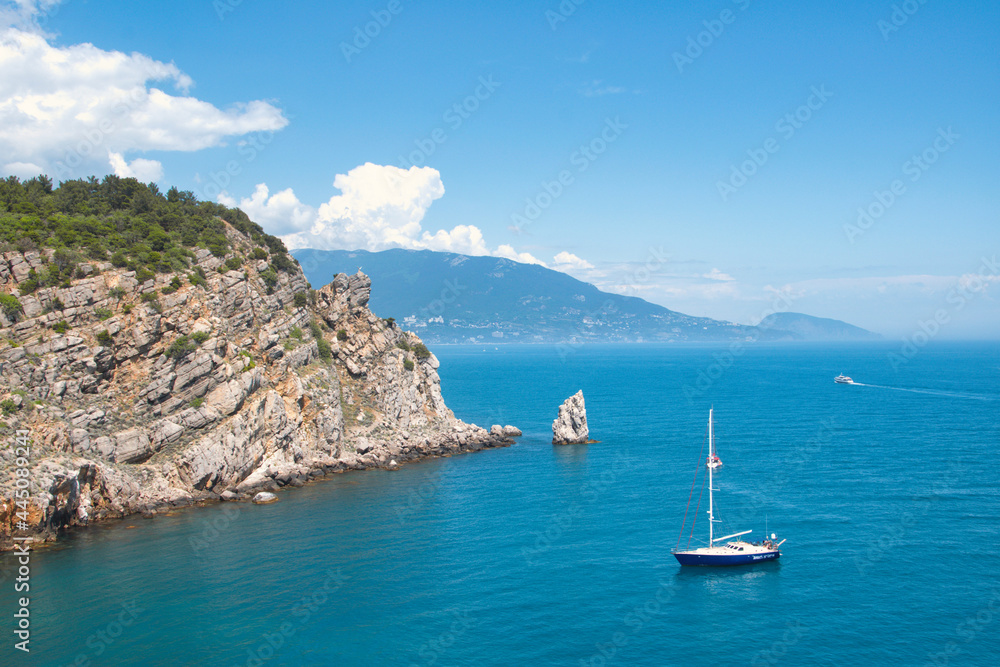 Blue yacht sailing in a rocky shore in Yalta