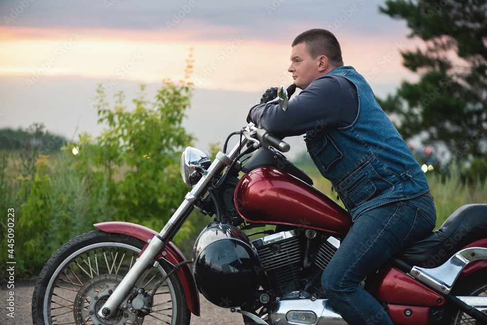 Tired motorbiker is sitting on the motorbike and thinks. Tired motorbiker is sitting on the motorbike and thinks.