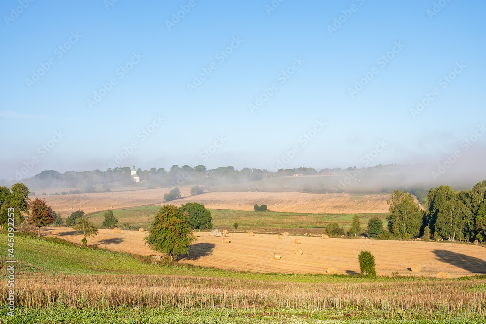 Fototapeta premium Rural landscape view at a valley with morning fog on the fields