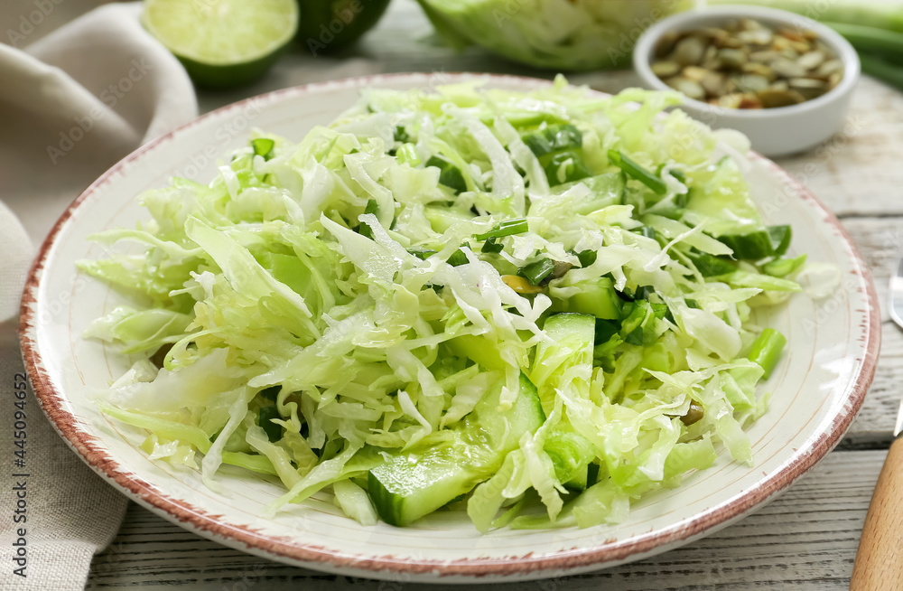 Plate with tasty cabbage salad on light wooden table Plate with tasty cabbage salad on light wooden table