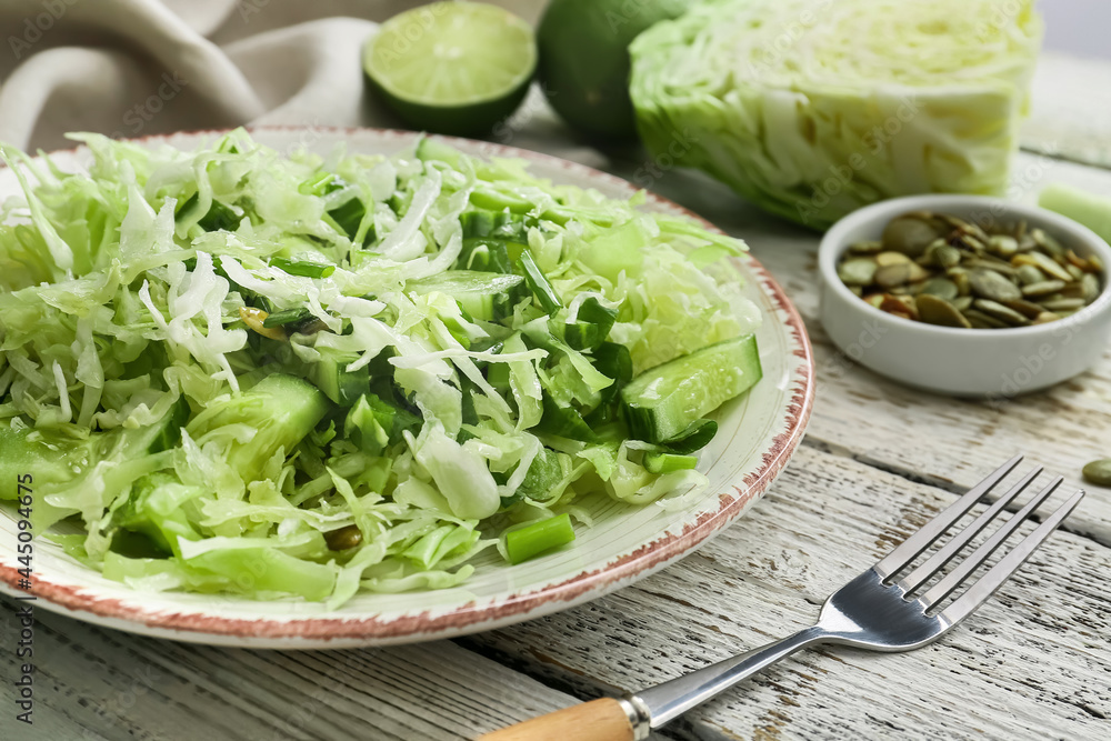 Plate with tasty cabbage salad on light wooden table Plate with tasty cabbage salad on light wooden table