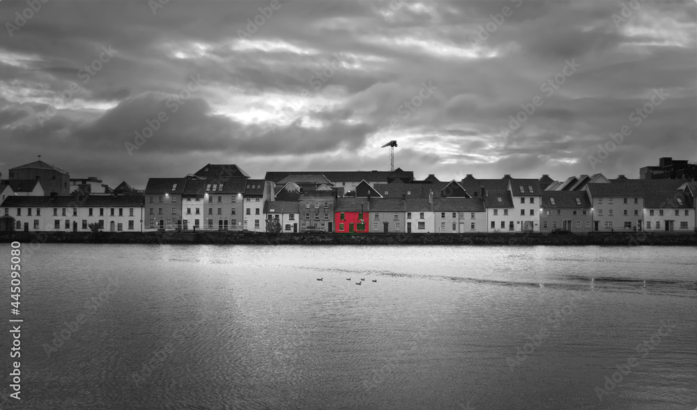 Black and white cityscape with red house in the middle at Claddagh by the Corrib River in Galway city, Ireland 