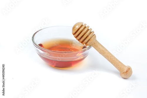 pure honey glass bowl with honey wooden spoon isolated on white background Clipping path.