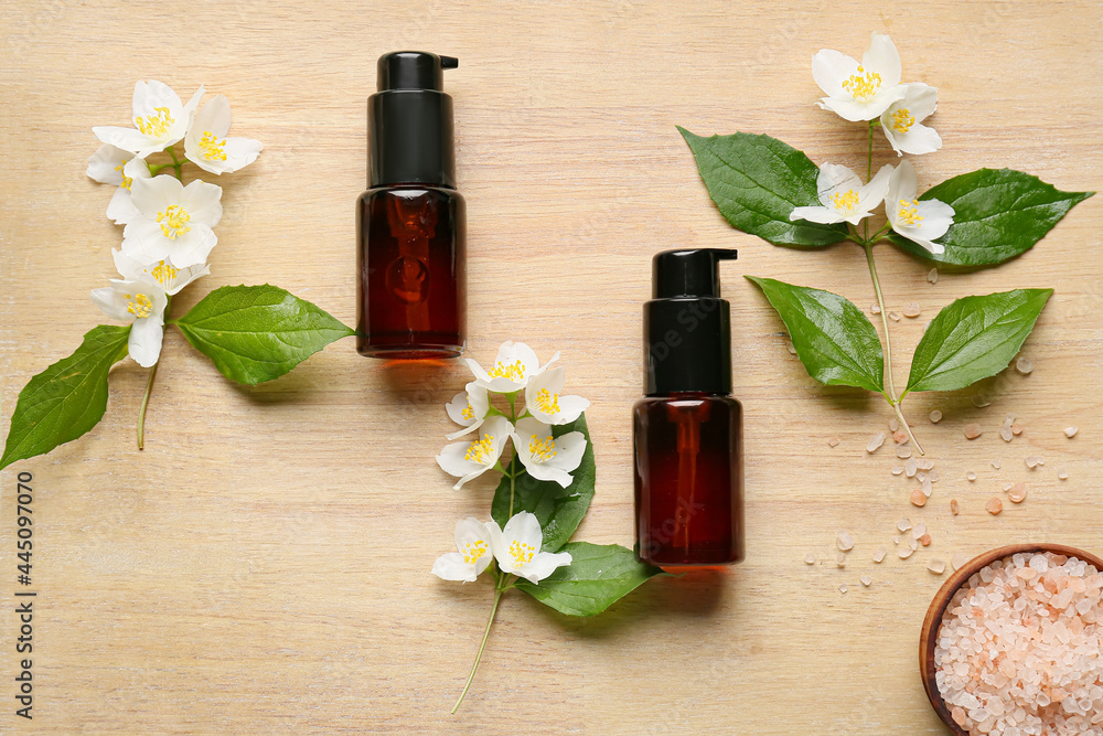 Bottles of cosmetic products, sea salt and jasmine flowers on wooden background Bottles of cosmetic products, sea salt and jasmine flowers on wooden background