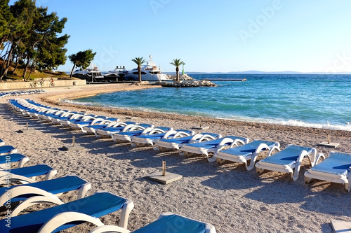 Deck chairs arranged on a beautiful beach near Split, Croatia. Selective focus. © jelena990