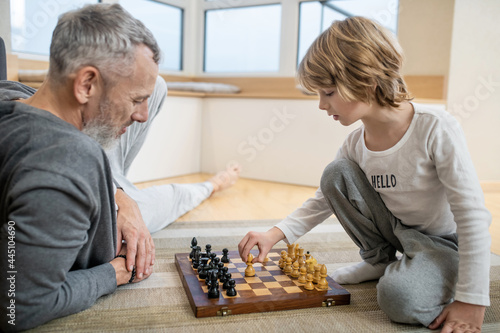 Father and son playing chess and looking involved