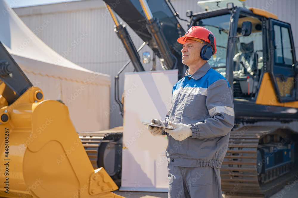 Concept man industrial 4.0 worker with online tablet. Bulldozer driver coal mine in uniform with helmet and headphones looking to side. Concept man industrial 4.0 worker with online tablet. Bulldozer driver coal mine in uniform with helmet and headphones looking to side.