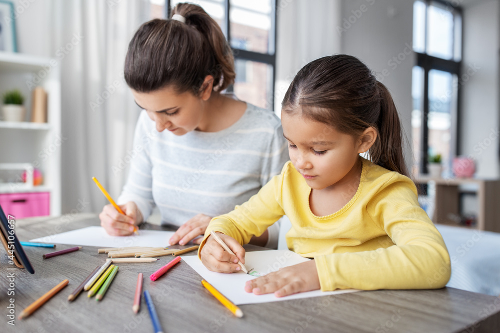 family, motherhood and leisure concept - mother spending time with her little daughter drawing with color pencils at home family, motherhood and leisure concept - mother spending time with her little daughter drawing with color pencils at home