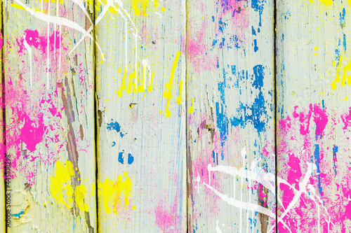 Old boards covered with bright multi-colored paints. Cheerful wooden background of bright fence.