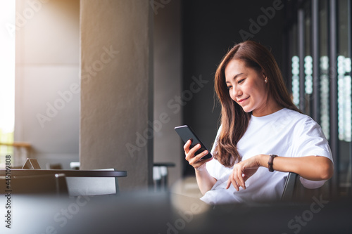 A beautiful young asian woman holding and using mobile phone