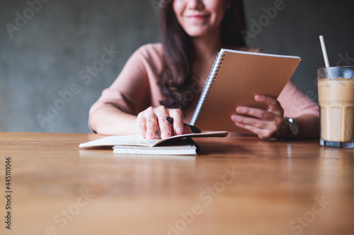Closeup image of a businesswoman working and writing on a notebook on wooden table