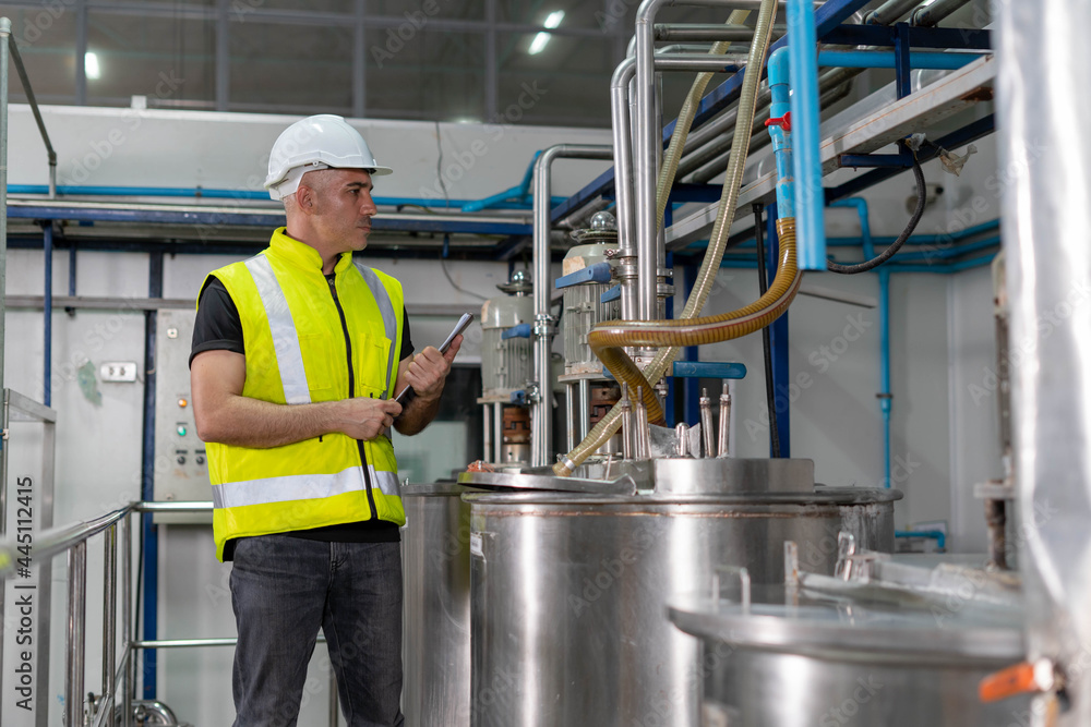 Engineers or factory managers wearing hard hats inspect the machines in the production line. The inspector opened the machine to test the system to meet the ISO standard. check and machine maintenance Engineers or factory managers wearing hard hats inspect the machines in the production line. The inspector opened the machine to test the system to meet the ISO standard. check and machine maintenance