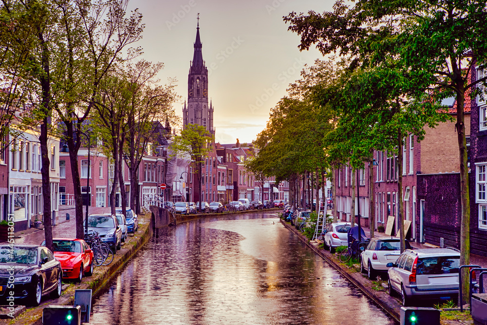 Dutch Travel Ideas. One of Traditional Dutch Channel Located in Old City Delft During Picturesque Sunset and Pouring Rain with Grey Clouds.