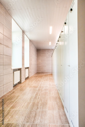 Indoors View of Long Industrial Tile Corridor With Metal Lockers.