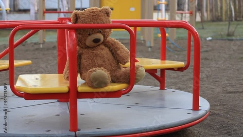 Forgotten Brown Teddy Bear on a Rotating Childrens Carousel in an Empty Playground. Concept Childhood, Psychology, Relationships, Growing up