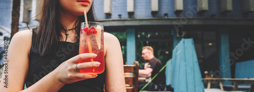 young teenager girl holding glass with a lemonade cocktail and drink in oudoor cafe photo