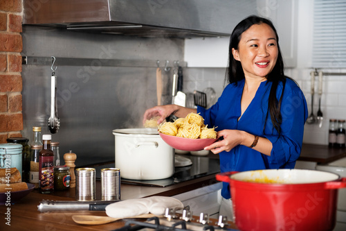 Wall Mural Asian woman cooking pasta in the kitchen