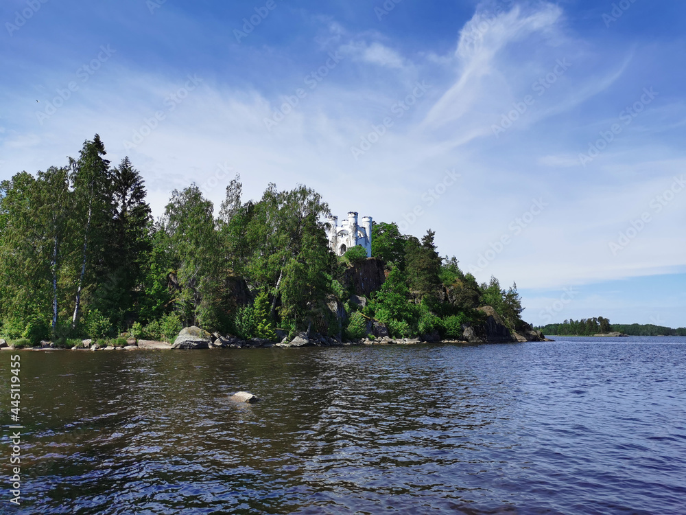 View from the shore of the Ludwigsburg Chapel on Ludwigstein Island in the Monrepos Rock Nature Park of Vyborg against a beautiful blue sky with clouds.