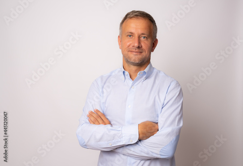 Handsome young man in blue shirt with arms crossed on white background © Danko