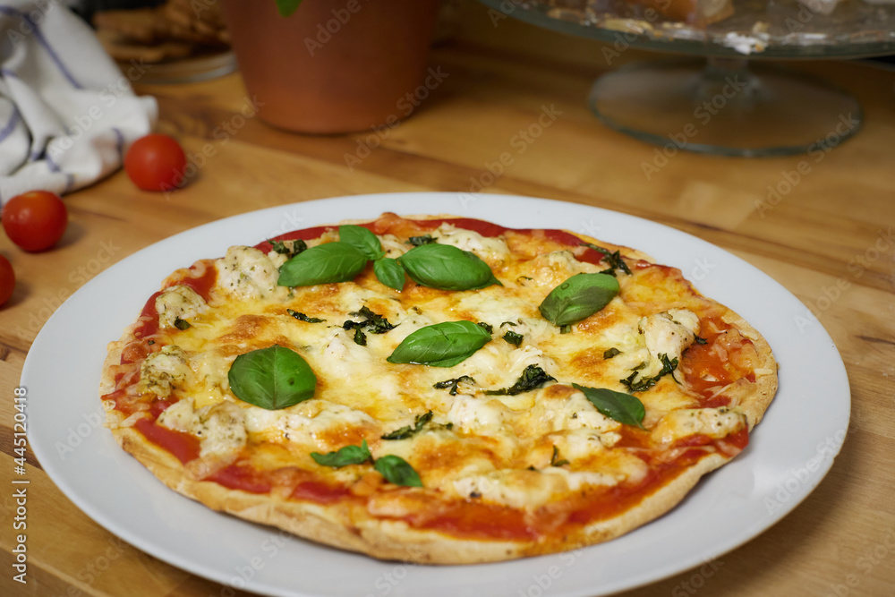 Homemade artisan pizza on white plate on wooden counter top Homemade artisan pizza on white plate on wooden counter top