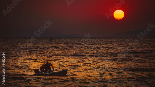 Pływający ludzie na morzu na tle ogromnego zachodzącego słońca