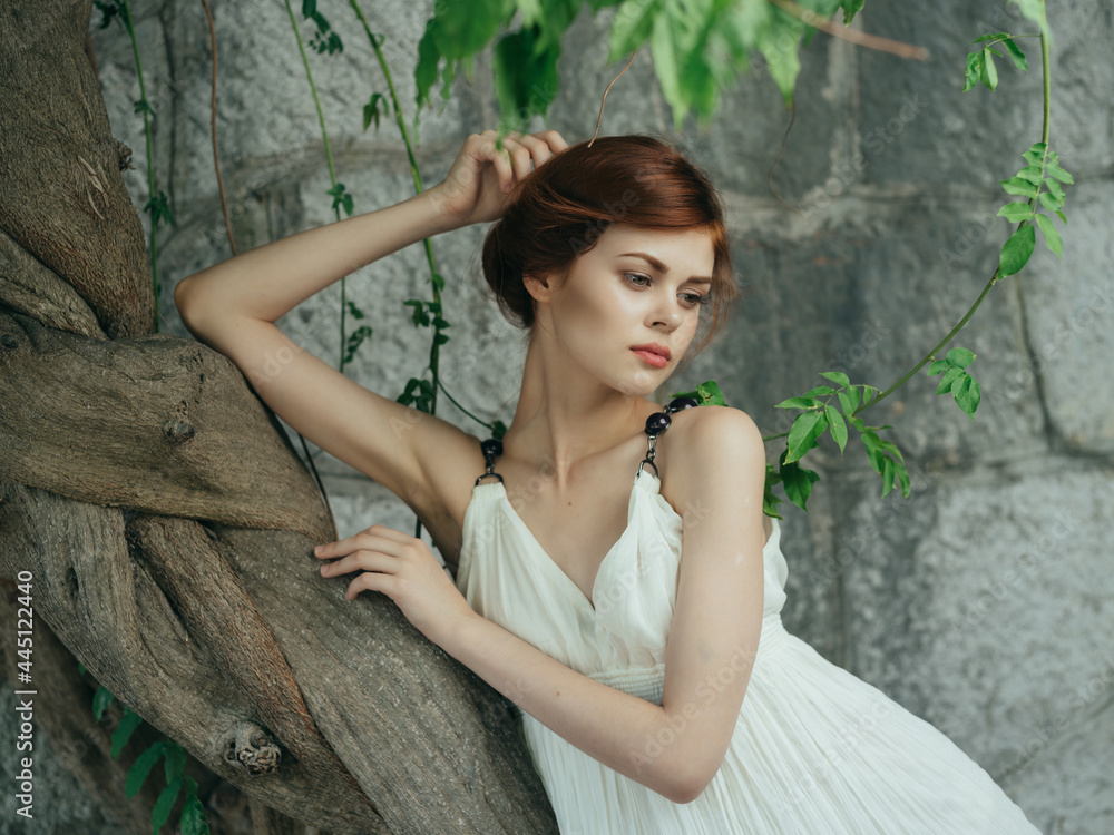 Woman in white dress near tree basing stone wall Greece Woman in white dress near tree basing stone wall Greece