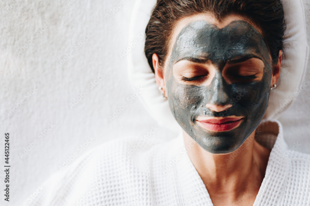 Woman relaxing with a charcoal facial mask Woman relaxing with a charcoal facial mask