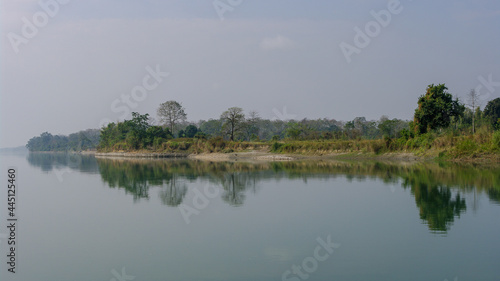 Peaceful landscape panorama of Brahmaputra river bank with trees reflection in water in remote rural Assam  India
