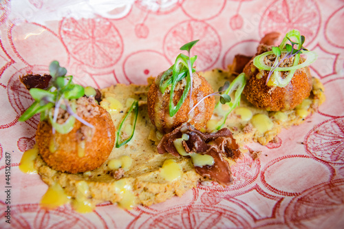  Agourmet meal of three falafels on a bed of humus and micro greens served on a pink plate. photo