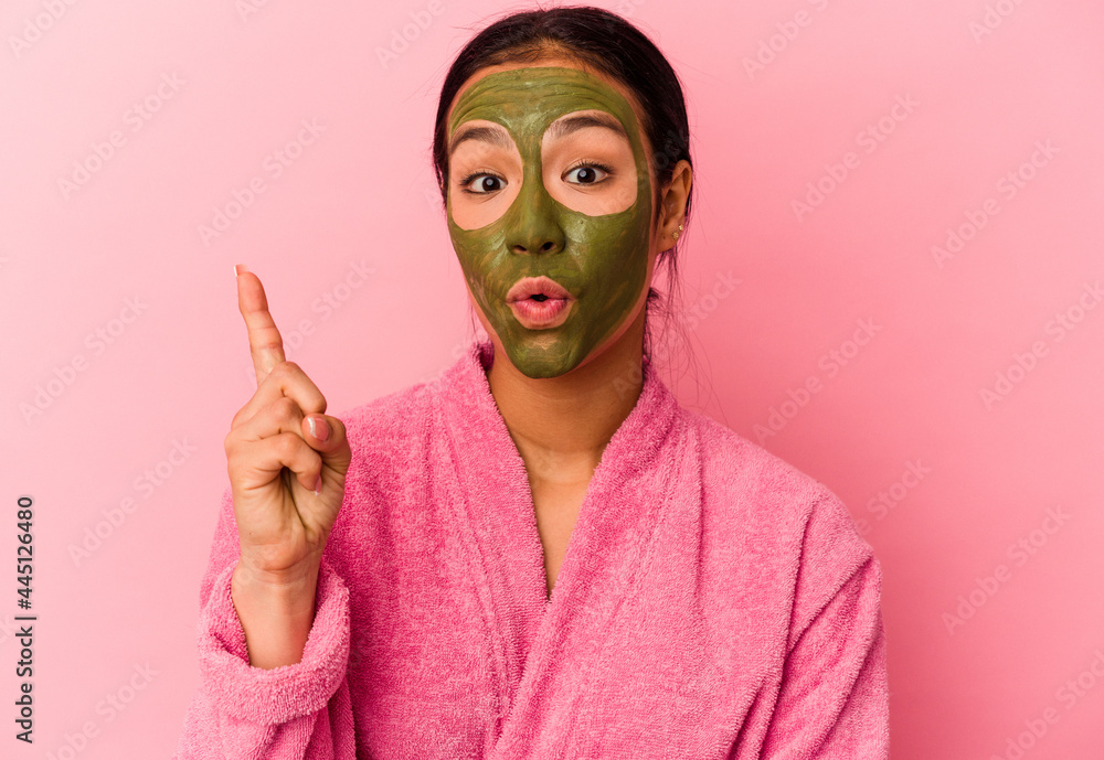 Young Venezuelan woman wearing a bathrobe and facial mask isolated on pink background having some great idea, concept of creativity. Young Venezuelan woman wearing a bathrobe and facial mask isolated on pink background having some great idea, concept of creativity.