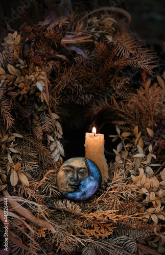 burning candle, symbolic moon, dry autumn leaves on dark natural background. old pagan, Wiccan, Slavic traditions. Witchcraft, esoteric spiritual ritual for mabon, halloween sabbath