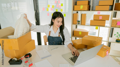 Starting an Asian Entrepreneur Small business, SME independent, young woman working at home with boxes on the floor and laptop online, marketing, packaging, transportation, SME, e-commerce concept