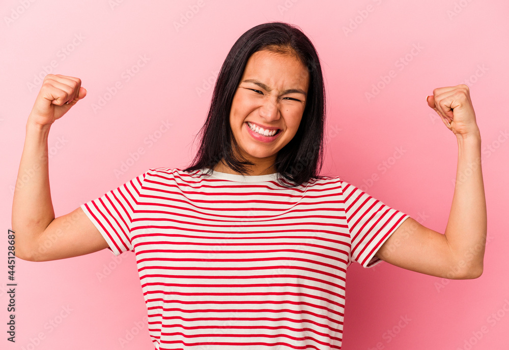 Young Venezuelan woman isolated on pink background showing strength gesture with arms, symbol of feminine power Young Venezuelan woman isolated on pink background showing strength gesture with arms, symbol of feminine power