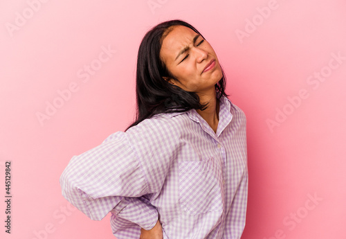 Young Venezuelan woman isolated on pink background suffering a back pain.