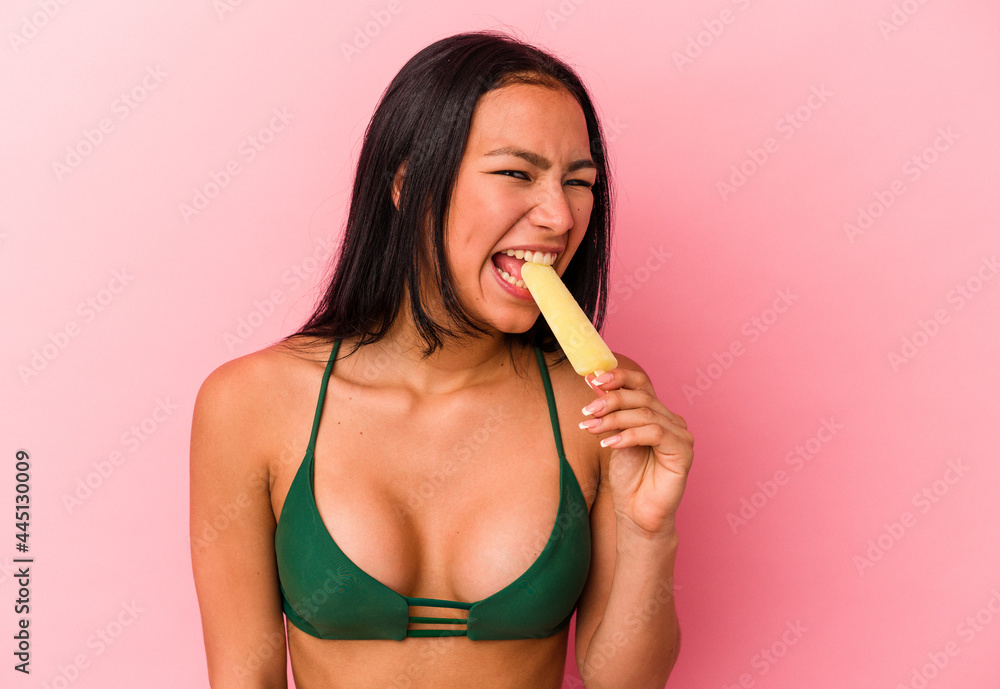 Young Venezuelan woman holding an ice cream isolated on pink background