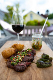 Grilled beef steak with chili ginger salsa on wooden table. Vertical background for a BBQ party in garden with short depth of field.