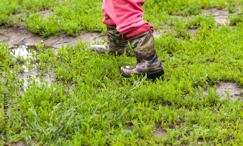 a small child in rubber boots runs through puddles